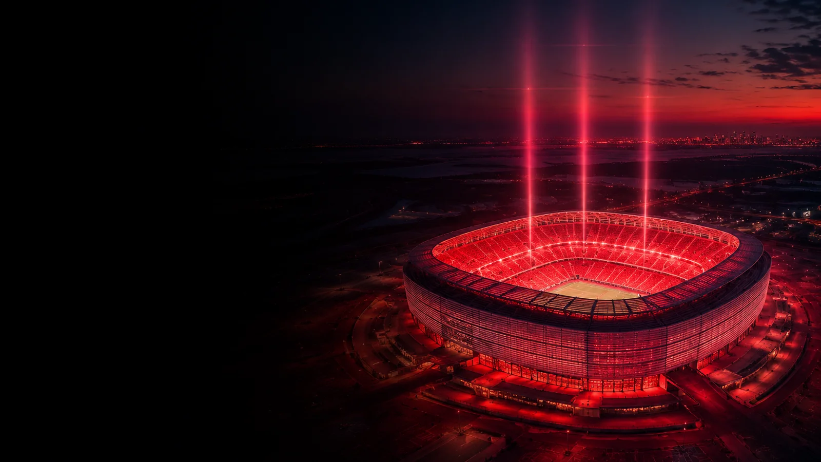 FIFA World Cup 2026 final venue MetLife Stadium at blue-hour — aerial view, crimson interior glow through the translucent scrim façade, three floodlight pillars rising into an indigo sky, deep void on the left